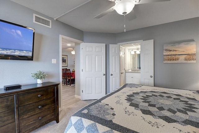 bedroom featuring light carpet, ceiling fan, and connected bathroom