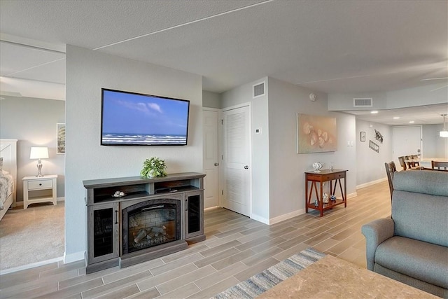 living room with light wood-type flooring, ceiling fan, and a textured ceiling