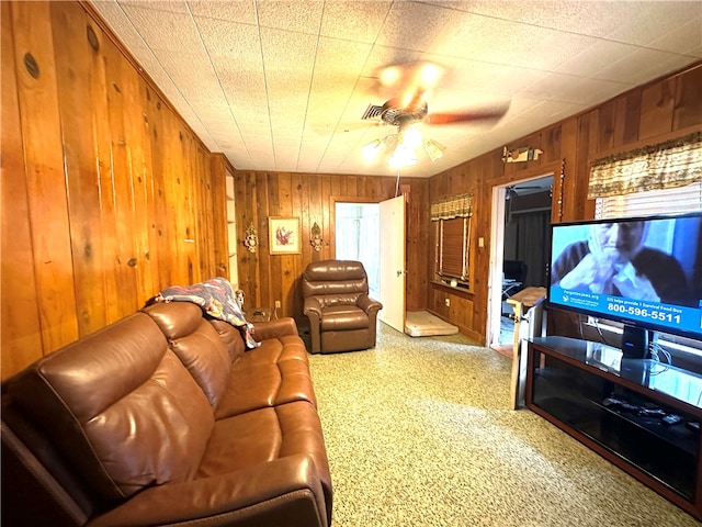 living room with carpet floors, wooden walls, and ceiling fan