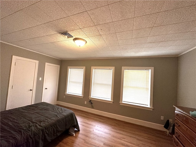 bedroom with wood-type flooring and ornamental molding