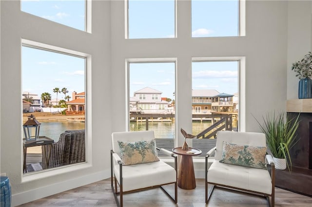 sitting room featuring a residential view, a water view, wood finished floors, and a wealth of natural light