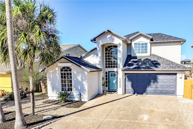 traditional-style house with a shingled roof, driveway, and stucco siding