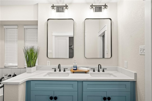 bathroom with a textured wall, a sink, and double vanity