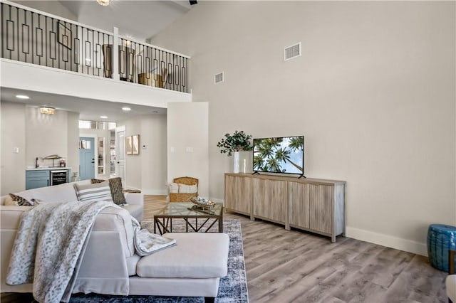 living area with light wood-style flooring, wine cooler, visible vents, and baseboards