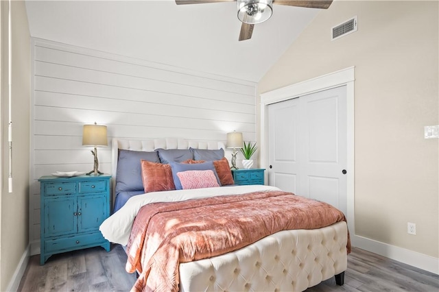 bedroom with light wood finished floors, baseboards, visible vents, lofted ceiling, and a closet