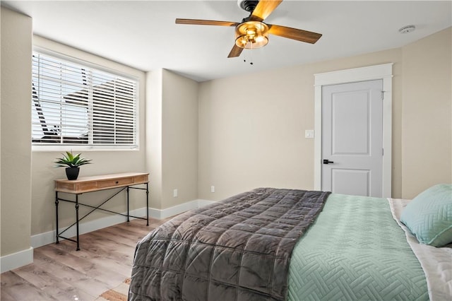 bedroom featuring ceiling fan, light wood finished floors, and baseboards