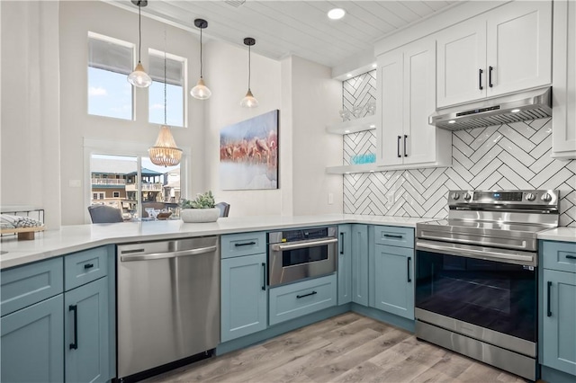 kitchen featuring open shelves, light countertops, decorative backsplash, appliances with stainless steel finishes, and under cabinet range hood