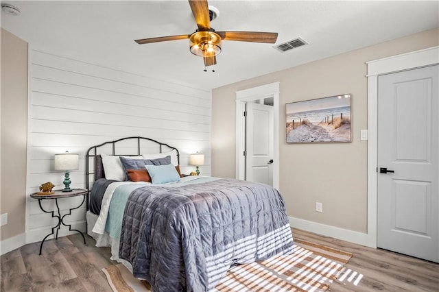 bedroom featuring a ceiling fan, baseboards, visible vents, and wood finished floors