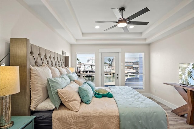 bedroom with access to outside, baseboards, a raised ceiling, and wood finished floors