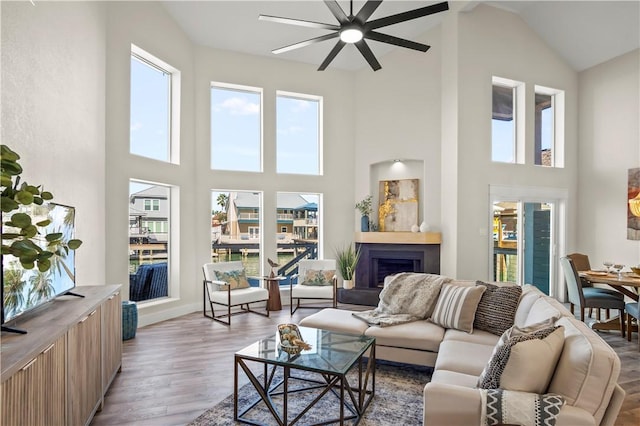 living area with light wood-style floors, a fireplace, and a high ceiling