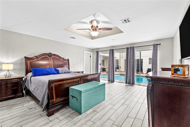 bedroom featuring access to outside, a tray ceiling, and ceiling fan