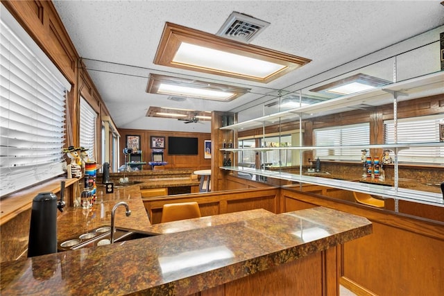 kitchen featuring dark stone countertops, ceiling fan, sink, and a healthy amount of sunlight