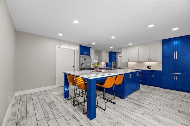 kitchen with a breakfast bar, appliances with stainless steel finishes, a center island, and white cabinets