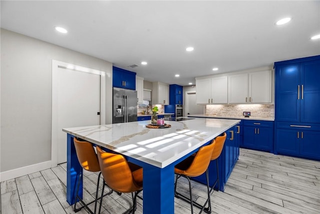 kitchen with a center island, stainless steel appliances, light stone counters, a breakfast bar, and light wood-type flooring