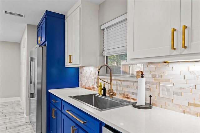 kitchen featuring white cabinets, blue cabinetry, and sink