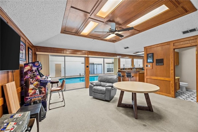 living room with a textured ceiling, light colored carpet, ceiling fan, and wooden walls