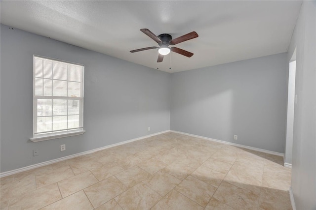 tiled spare room with baseboards and ceiling fan