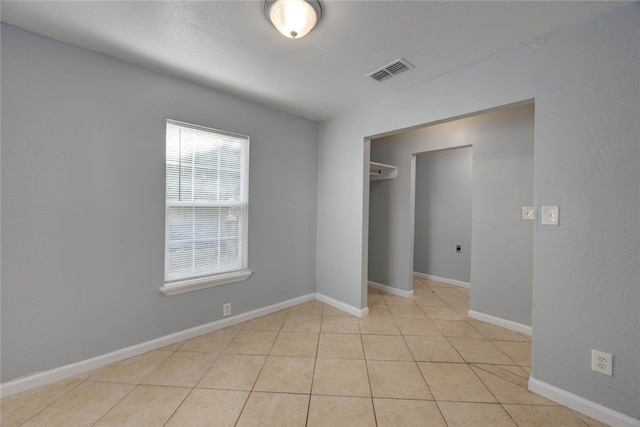 unfurnished bedroom featuring light tile patterned flooring, visible vents, and baseboards