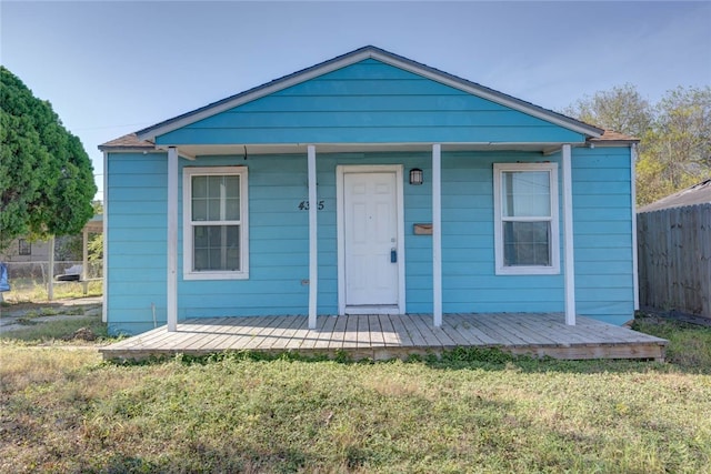 bungalow featuring covered porch, a front yard, and fence