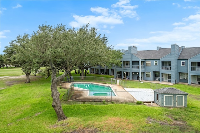 view of pool featuring a storage shed and a lawn