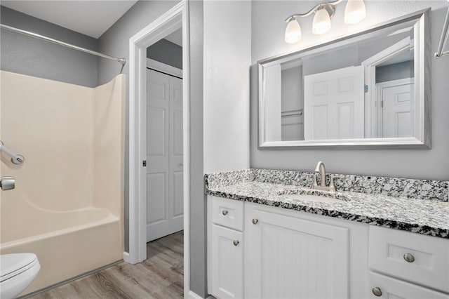 full bathroom featuring hardwood / wood-style flooring, shower / washtub combination, vanity, and toilet