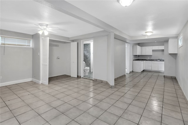 basement featuring baseboards, ceiling fan, and a healthy amount of sunlight