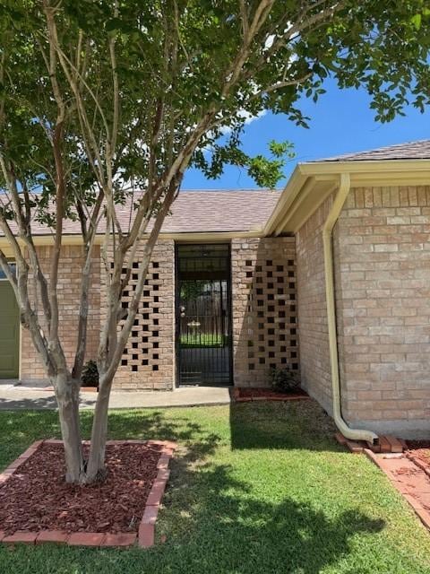 4202 Wolf Creek Dr, Corpus Christi, TX 78413 - view of exterior entry featuring a yard, brick siding, and roof with shingles