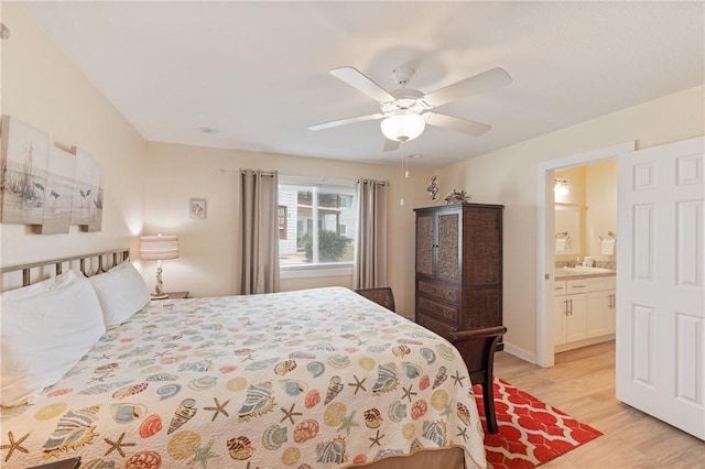bedroom with ensuite bathroom, a sink, light wood-style flooring, and a ceiling fan