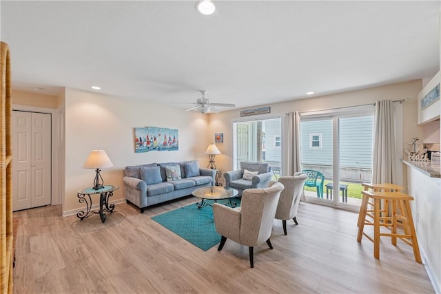 living room featuring baseboards, a ceiling fan, and light wood-type flooring