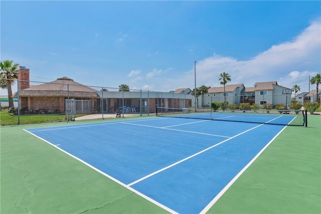 view of tennis court with fence and a residential view