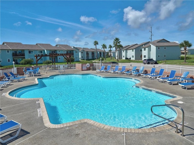 community pool with a residential view, fence, and a patio area