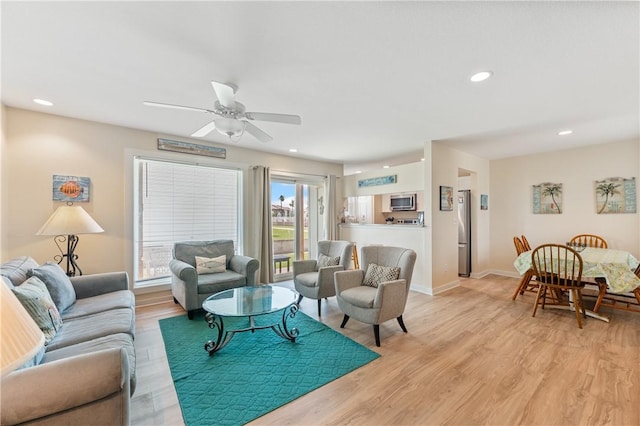 living area with light wood-style floors, baseboards, ceiling fan, and recessed lighting