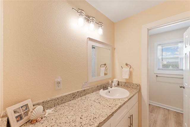 bathroom featuring baseboards, wood finished floors, and vanity