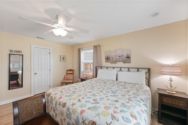 bedroom featuring baseboards, ceiling fan, wood finished floors, and visible vents