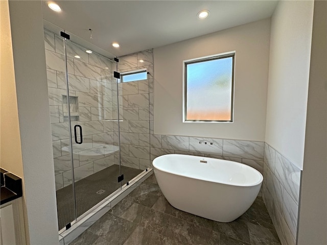 bathroom featuring plus walk in shower and tile walls