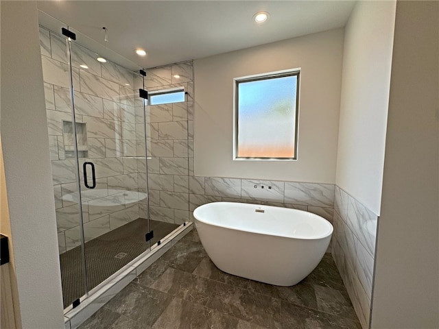 bathroom with tile walls and separate shower and tub