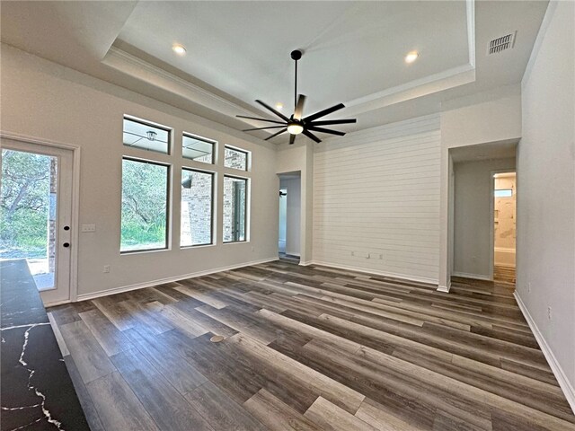 unfurnished living room with ornamental molding, dark hardwood / wood-style flooring, ceiling fan, and a tray ceiling