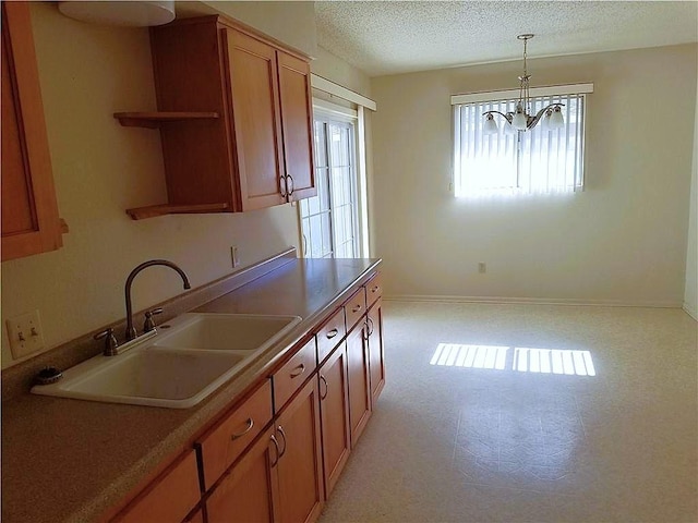 kitchen with a chandelier, a textured ceiling, brown cabinets, decorative light fixtures, and light flooring