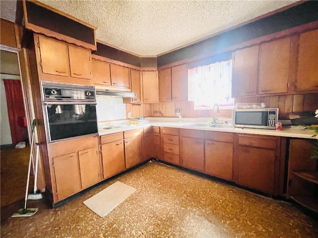 kitchen featuring a sink, light countertops, under cabinet range hood, stainless steel microwave, and black oven