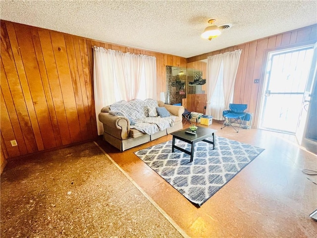 living room featuring wood walls and a textured ceiling