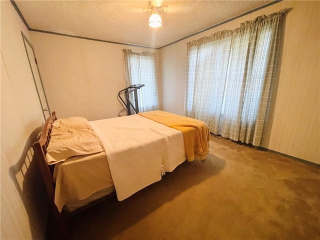 bedroom featuring carpet flooring, wood walls, and a textured ceiling