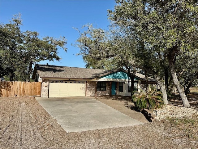 ranch-style home with driveway, roof with shingles, a garage, brick siding, and fence