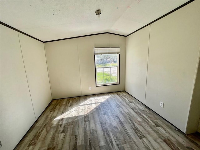 unfurnished room with ornamental molding, vaulted ceiling, and wood finished floors