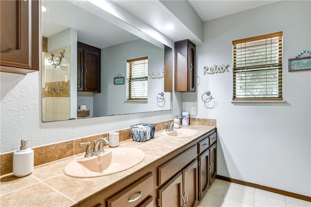 bathroom featuring double vanity, a sink, baseboards, and tile patterned flooring