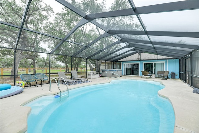 pool with glass enclosure, a hot tub, a patio area, and an outdoor hangout area