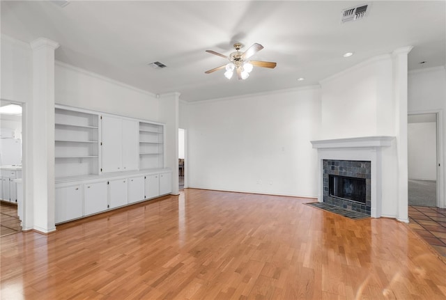 unfurnished living room featuring ornamental molding, a tiled fireplace, ceiling fan, and light hardwood / wood-style floors