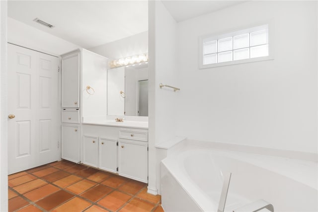 bathroom with tile patterned flooring, a washtub, and vanity