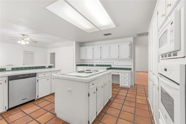 kitchen featuring tile countertops, a kitchen island, backsplash, white cabinetry, and white appliances