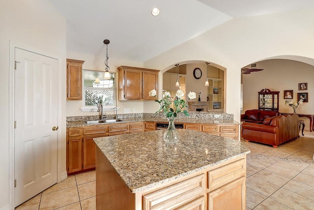6613 Belvoir Ave, Corpus Christi, TX 78414 - kitchen with arched walkways, light tile patterned floors, vaulted ceiling, light stone counters, and a kitchen island