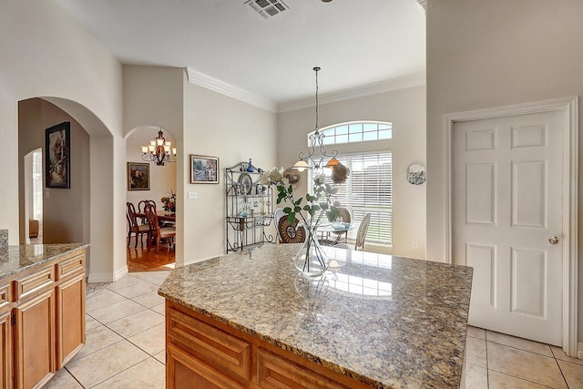 6613 Belvoir Ave, Corpus Christi, TX 78414 - kitchen with a chandelier, light tile patterned floors, arched walkways, light stone counters, and brown cabinets